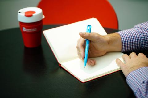 A student writing in a notebook at Imperial College Business School