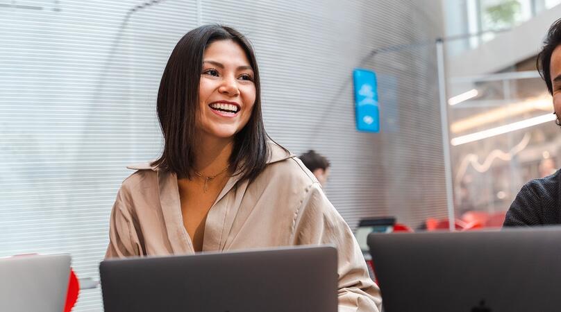 A young woman on a mac laptop smiling