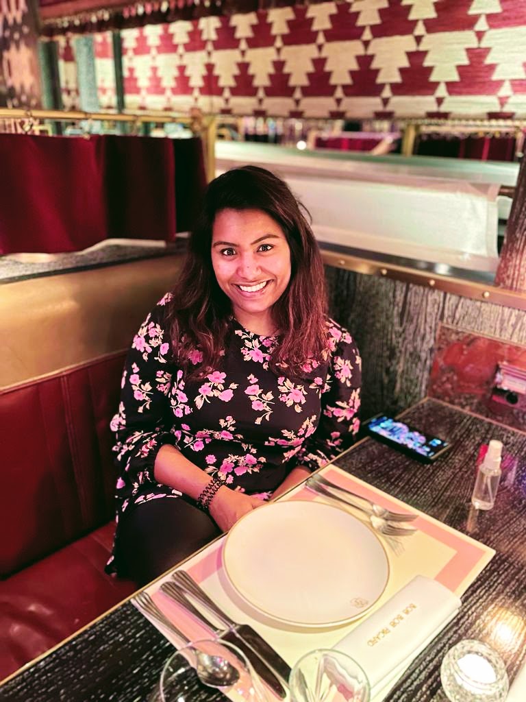 Sarah Jasim sitting at a table in a restaurant smiling at the camera