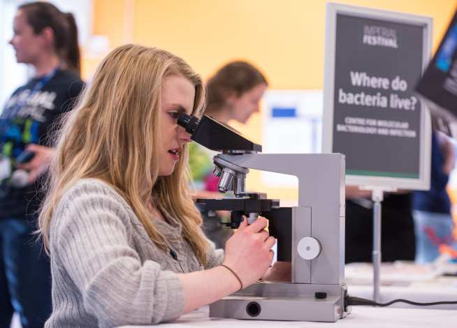 Visitor looking down microscope at Imperial Festival 2015