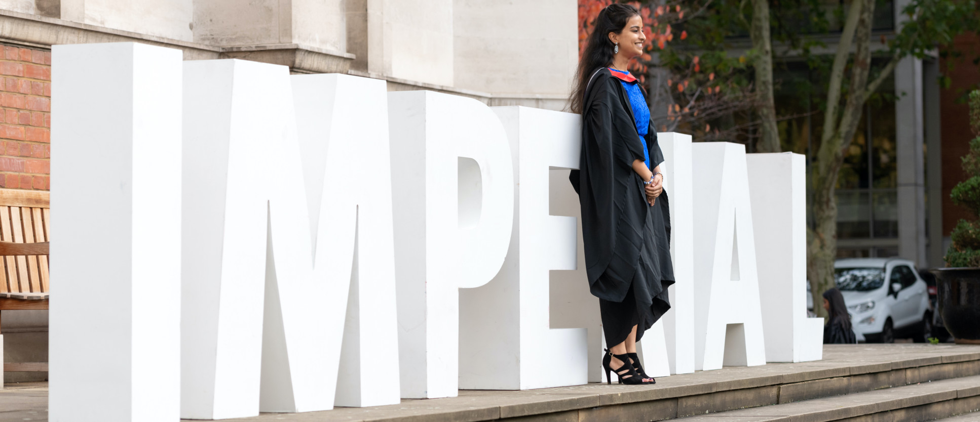 Student at Graduation in front of Imperial sign