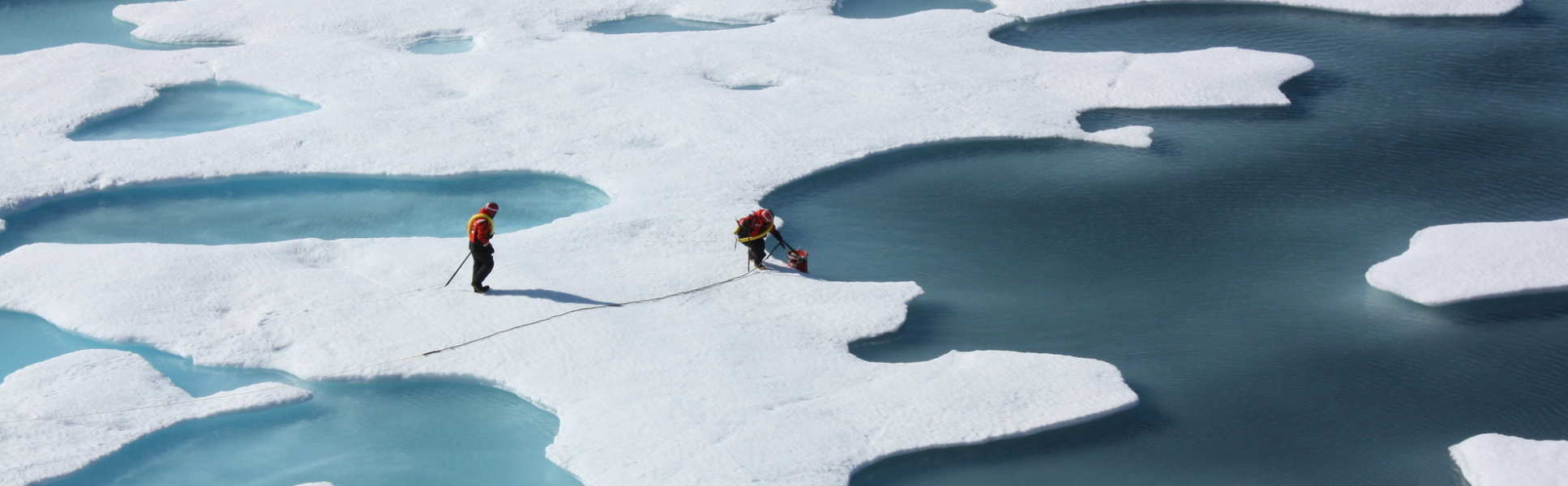 Crew from the U.S. Coast Guard Cutter Healy on ice surrounded by water, retrieving a canister