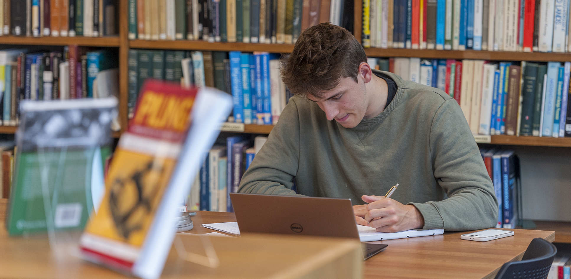 Student writing in a library