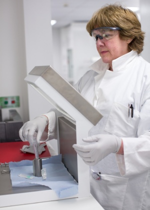 Hope McDevitt, PET radiographer, prepares radioactive tracer behing thick lead glass for protection