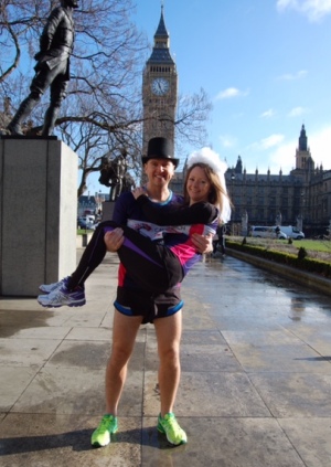 Paul Elliott and his partner Laura pose in running gear and a veil and top hat in front of the houses of parliament