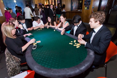 people sit around green topped table with card dealer