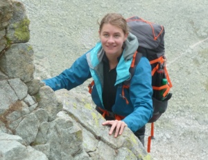 Dr Susan Little, with hair scraped back, climbing a cliff face