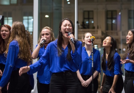 group of young women in blue shirts singing with microphones
