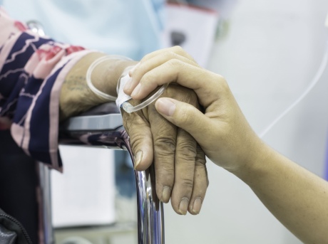 Close up of family member's hand on top of intensive care patient's hand in comforting manner