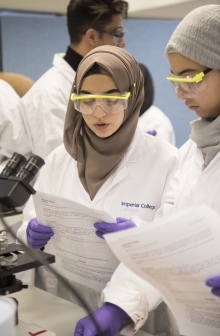 Two researchers wearing protection goggles holding and looking over documents