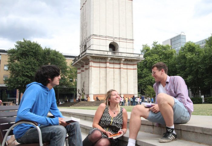 Three students chatting on the Queen's Lawn about how satisfied they are at Imperial College.