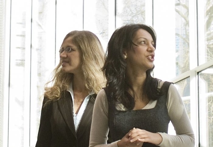 Two women standing in the South Kensington campus main foyer.