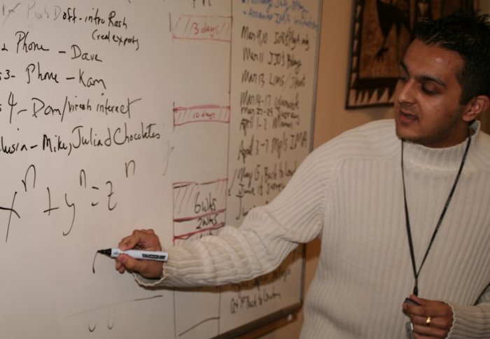 Teacher writing a mathematics formula on a whiteboard.