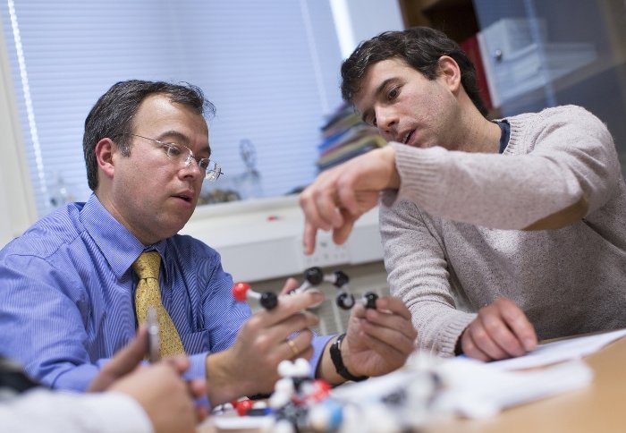 A student and teacher discuss a molecular model.