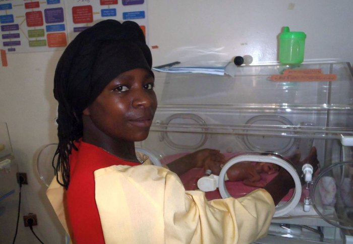 A mother cradles her premature baby in an incubator