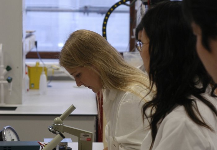 Women studying a microscope in a lab.