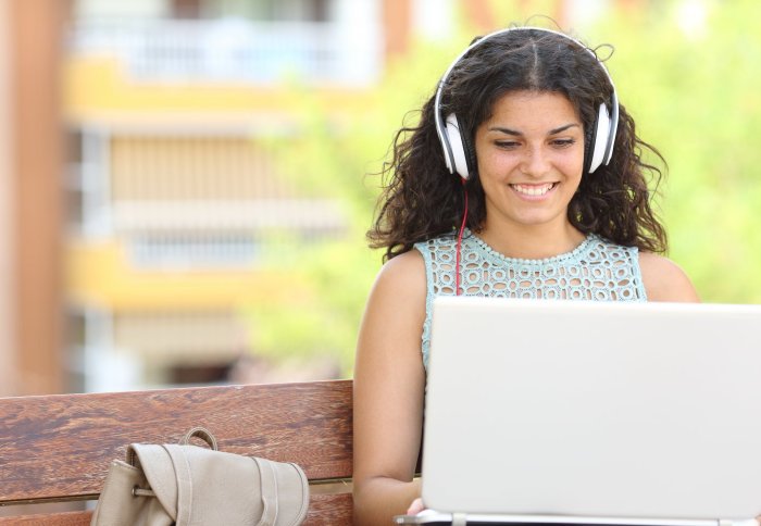 Female student using a laptop and wearing headphones
