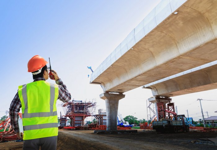 Man in construction gear looking at a bridge under construction