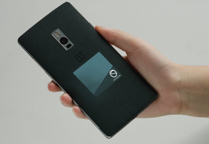 Back of smartphone with stick-on sensor, held in hand