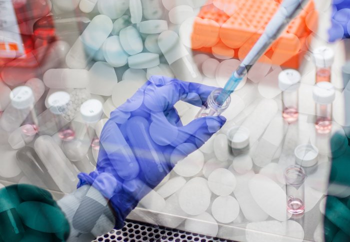 Researchers hand with a pipette with medication in the background