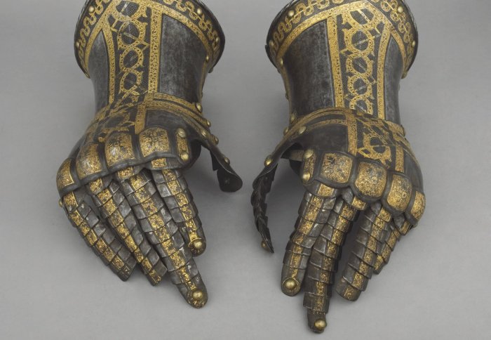 A pair of grey metal gauntlets inlaid with gold