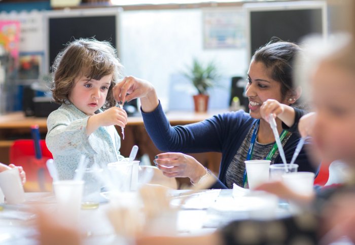 young girl uses a pipette with the help of a young woman