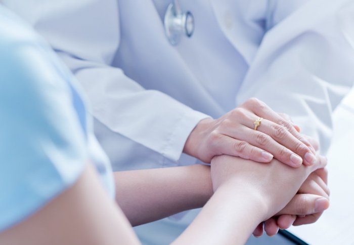 Doctor reassuringly holding patient's hand