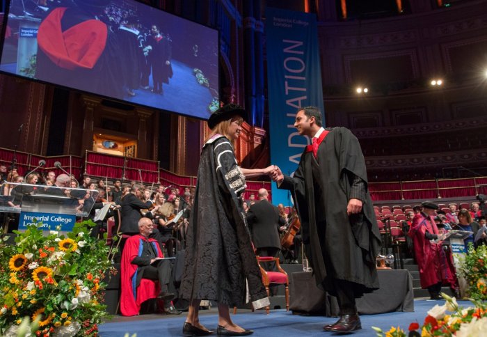 Student on stage shaking hands with senior college staff at graduation ceremony