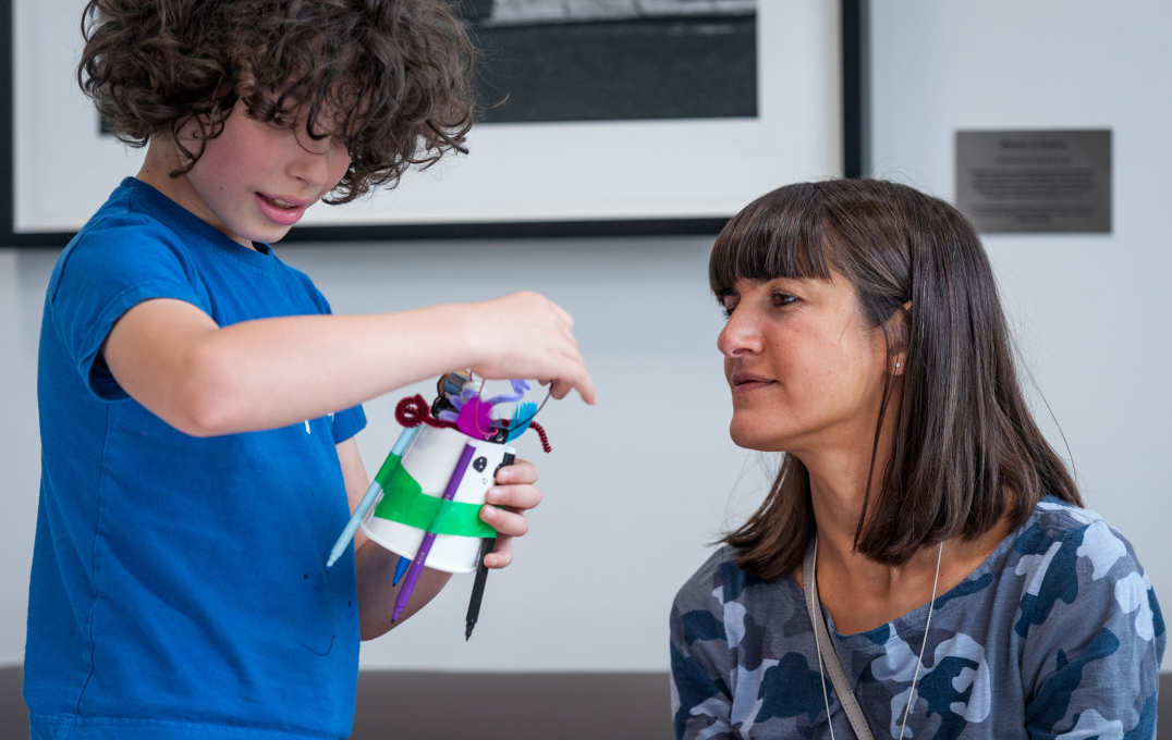 A mother watches her son make a robot