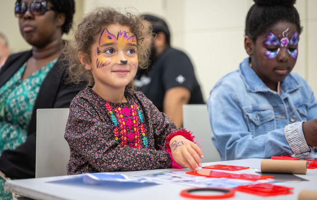 Two children with their faces painted taking part in an activity