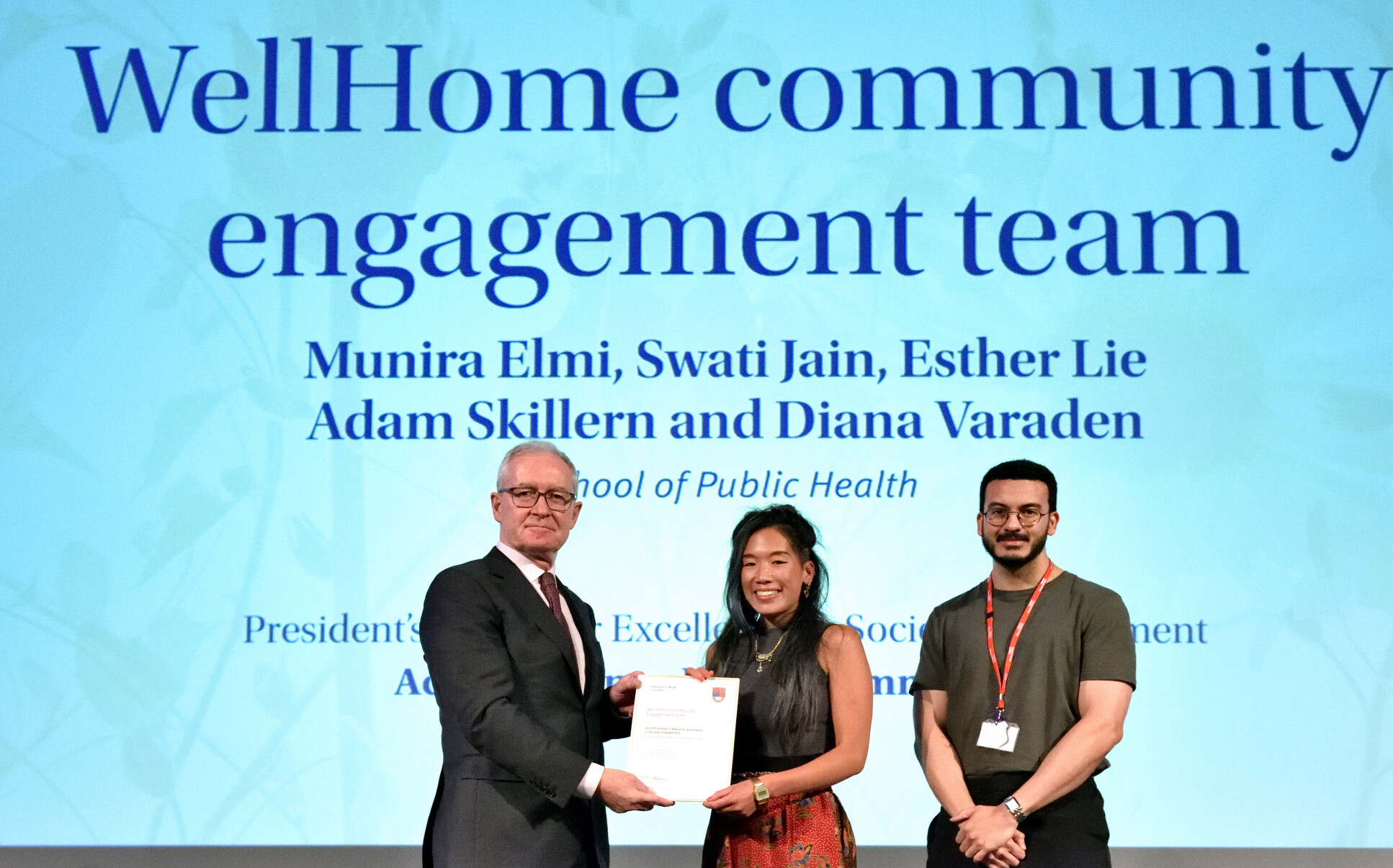 Representatives from the WellHome Community Engagement Team receive an award from President Hugh Brady