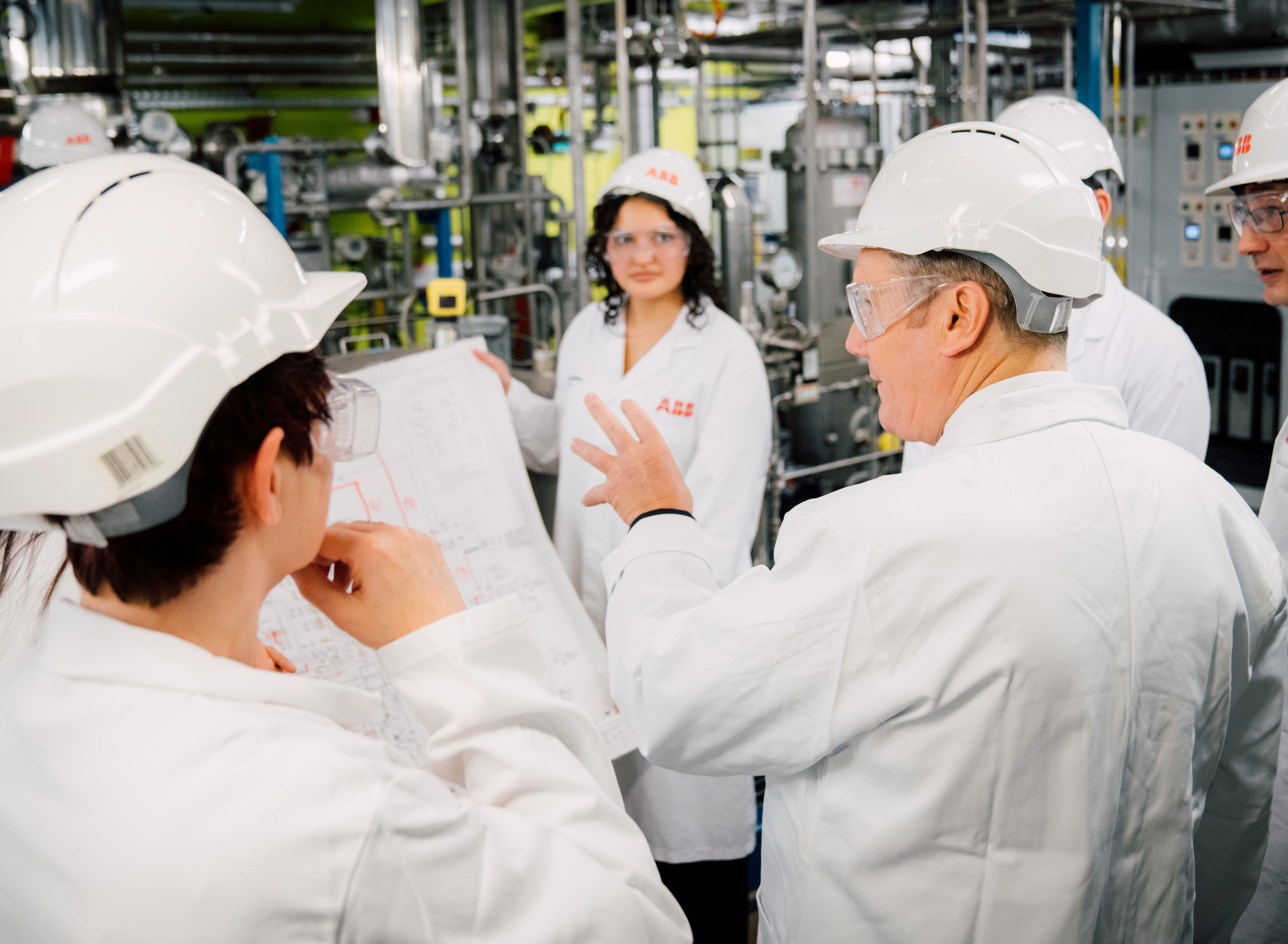 People in labcoats and hardhats looking at map in a plant