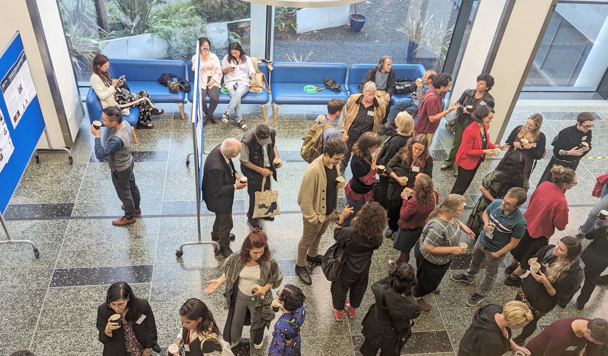 Conference attendees talking to each other and reading posters during a break in the SERCH conference.