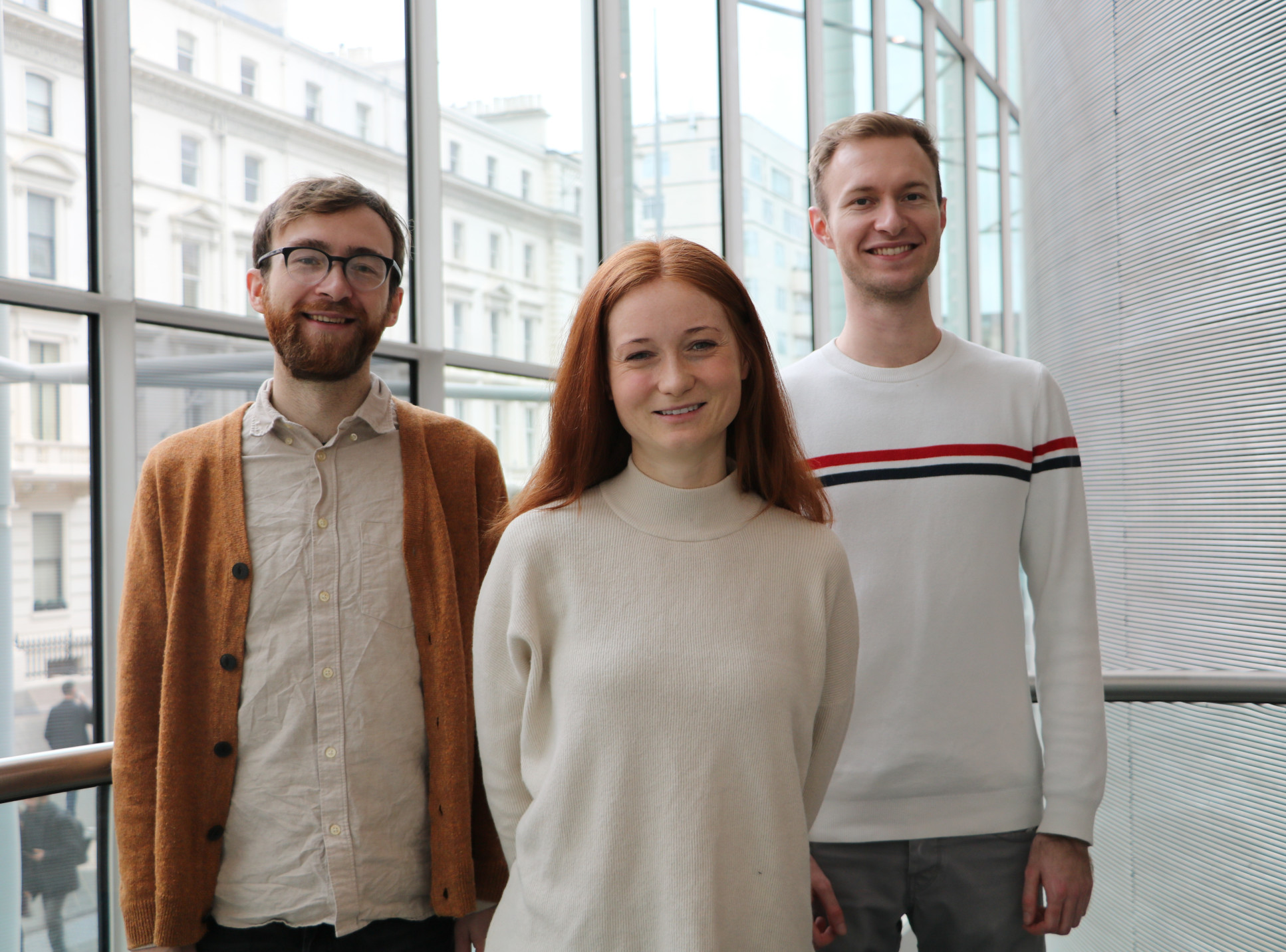 Three people stand in the College's main entrance